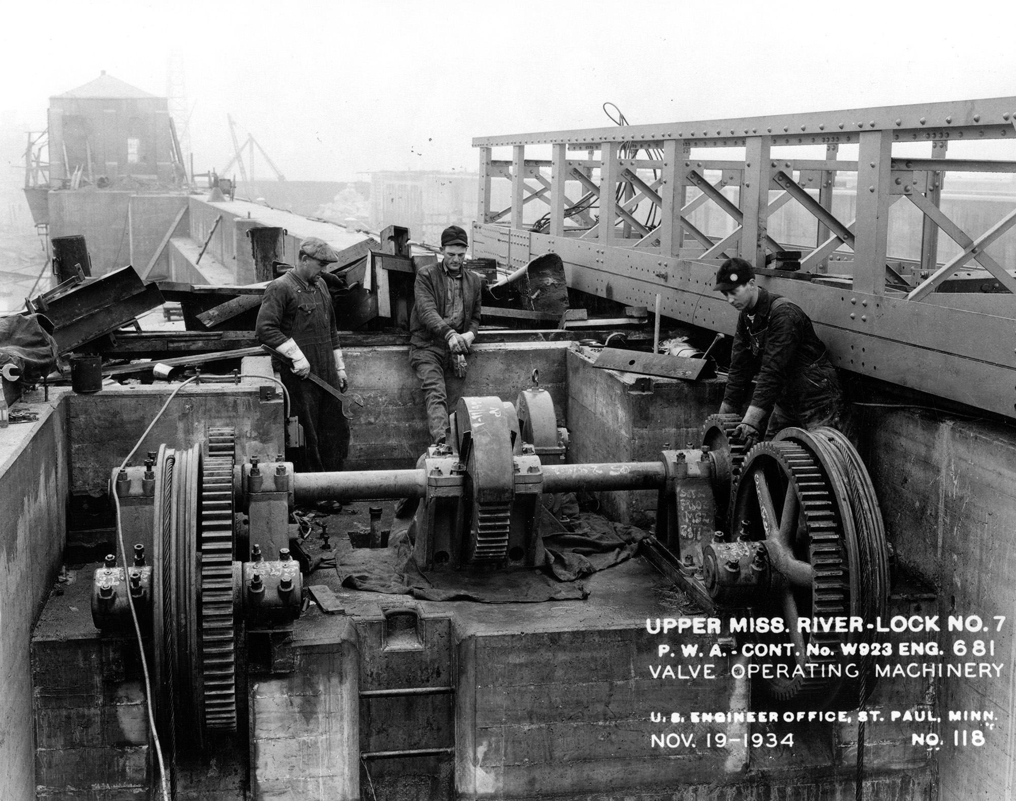 Men on river dam machinery conducting repairs