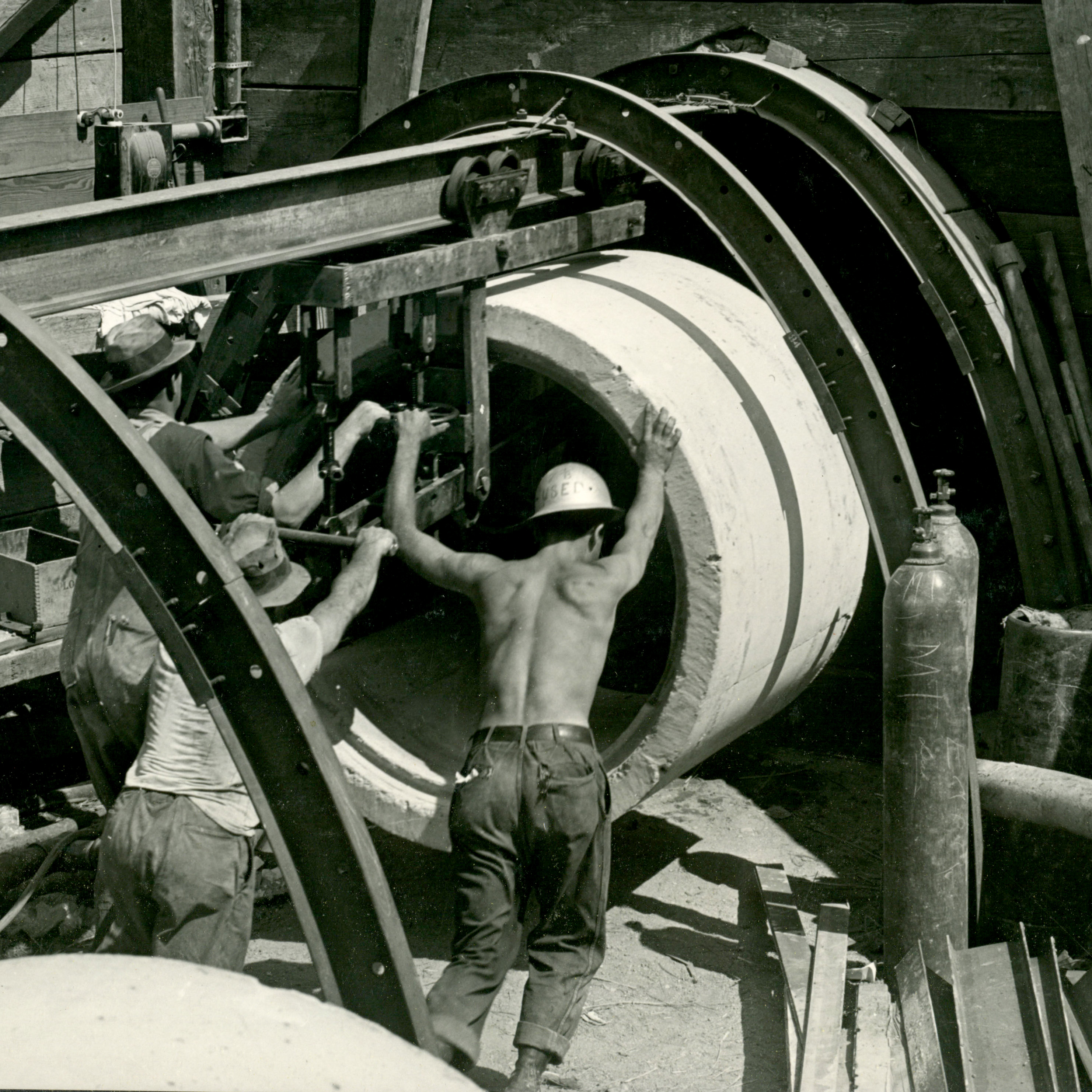 Three men push a large round section of tunnel into place