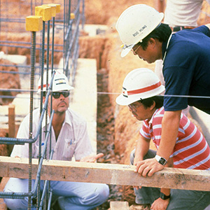 Three men in hardhats at a foundation construction site