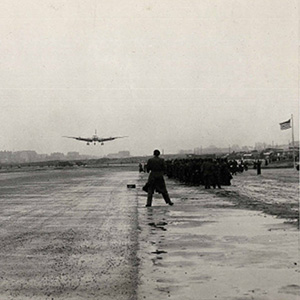 Man standing on runway as an airplane approaches to land