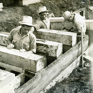 Three men in hats building a timber structure below ground
