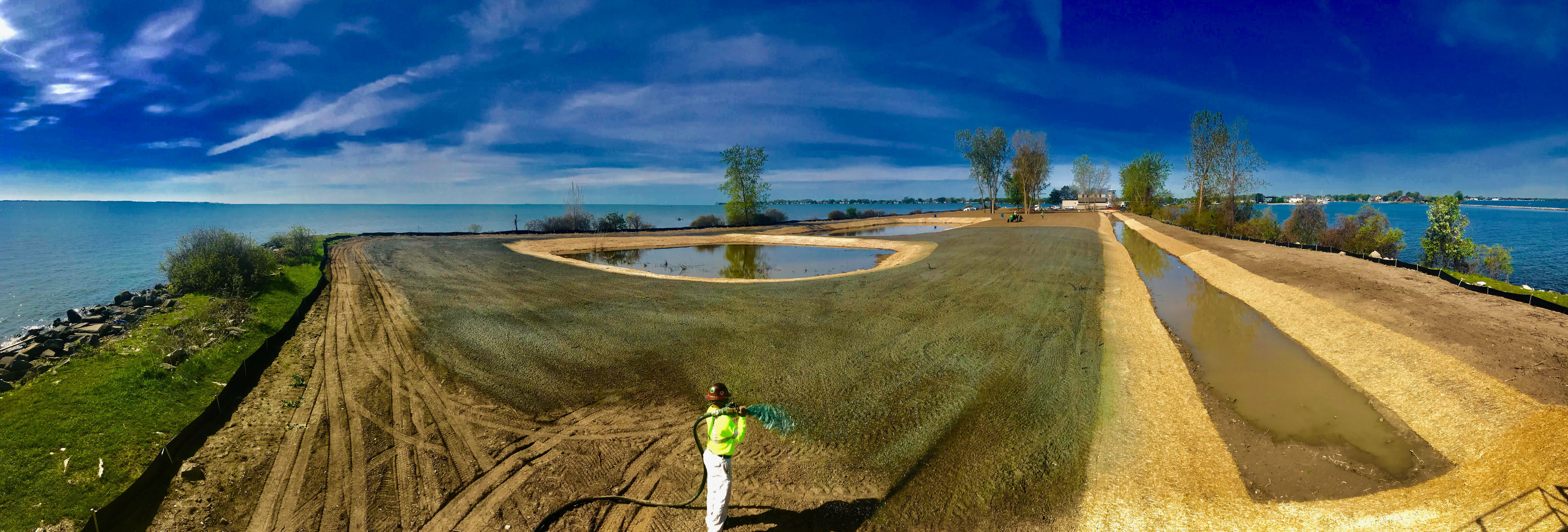 Image of a man in a hardhat holding a hose in an area with water drainage.