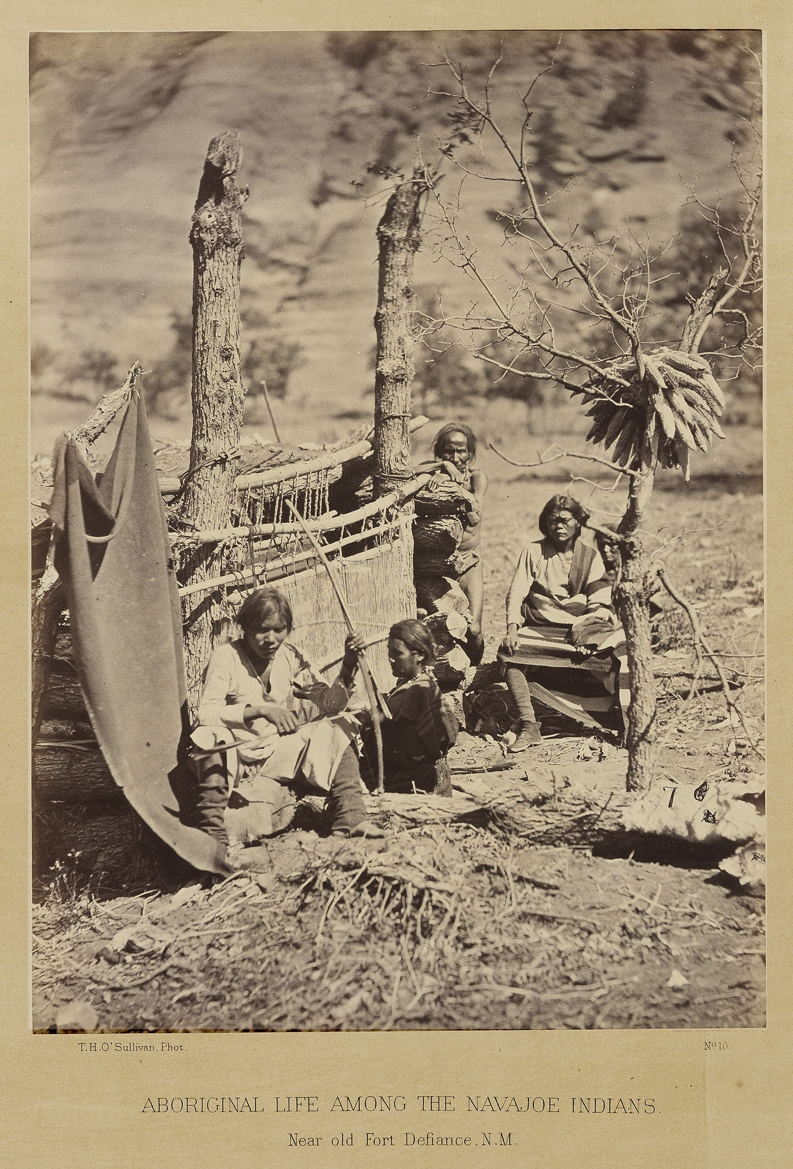 Four Navajo people sit outside near trees