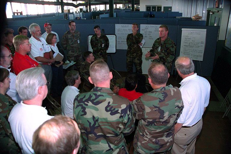 People in military uniform and civilian clothes in an office setting
