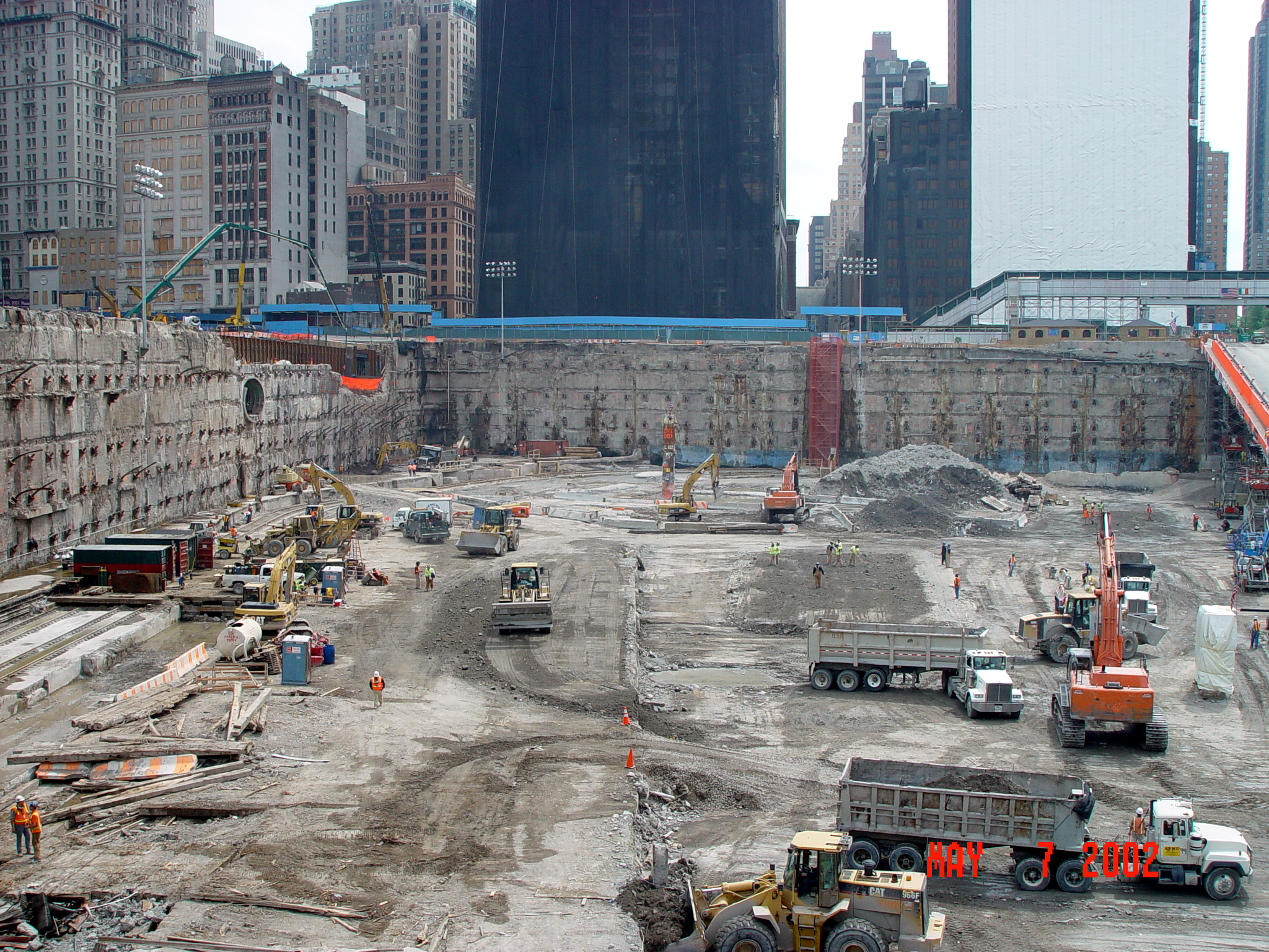 A large square excavated hole with construction machinery within A large square excavated hole with construction machinery within
