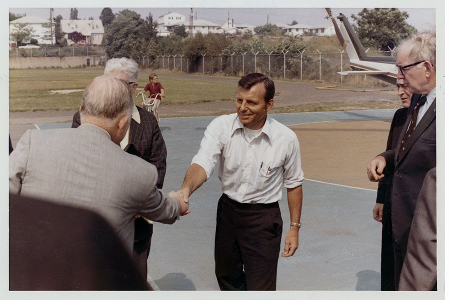 Several men shake hands on a runway