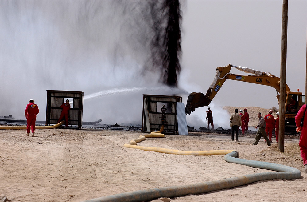 men trying to stop oil from spraying into the sky from a well